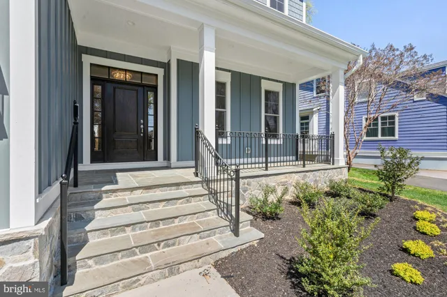 a view of a house with potted plants and a bench in front of house
