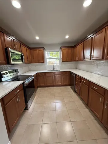 a large kitchen with stainless steel appliances granite countertop a stove sink and cabinets