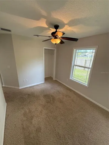 an empty room with windows and fan