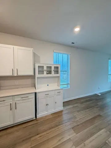a kitchen with cabinets wooden floor and stainless steel appliances