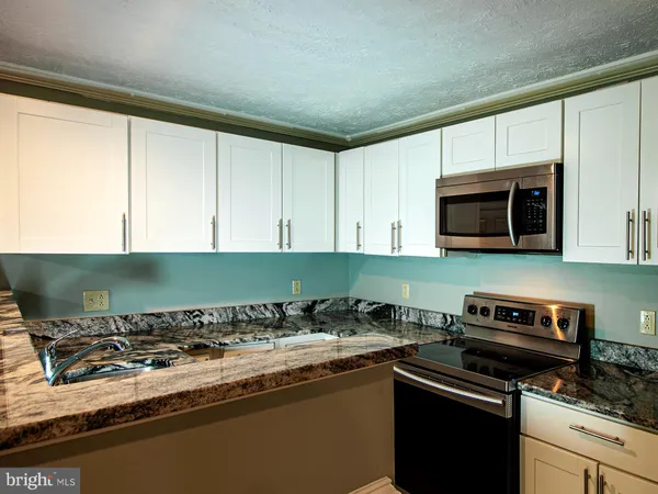 a kitchen with granite countertop a sink and a stove top oven