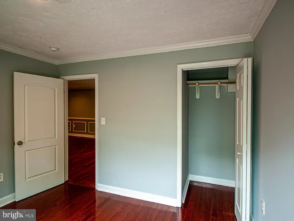 a view of an empty room with wooden floor and closet