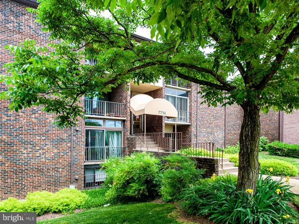 a front view of a house with a garden and trees