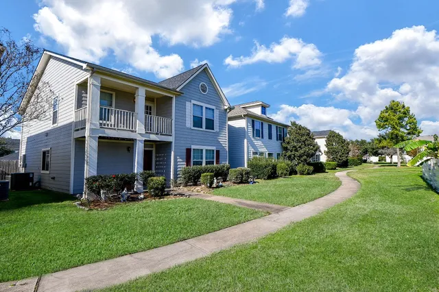 a view of a brick building next to a yard with big trees