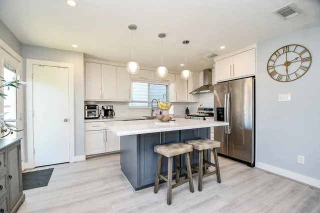 a kitchen with kitchen island a refrigerator a stove a sink and a stove with wooden floor