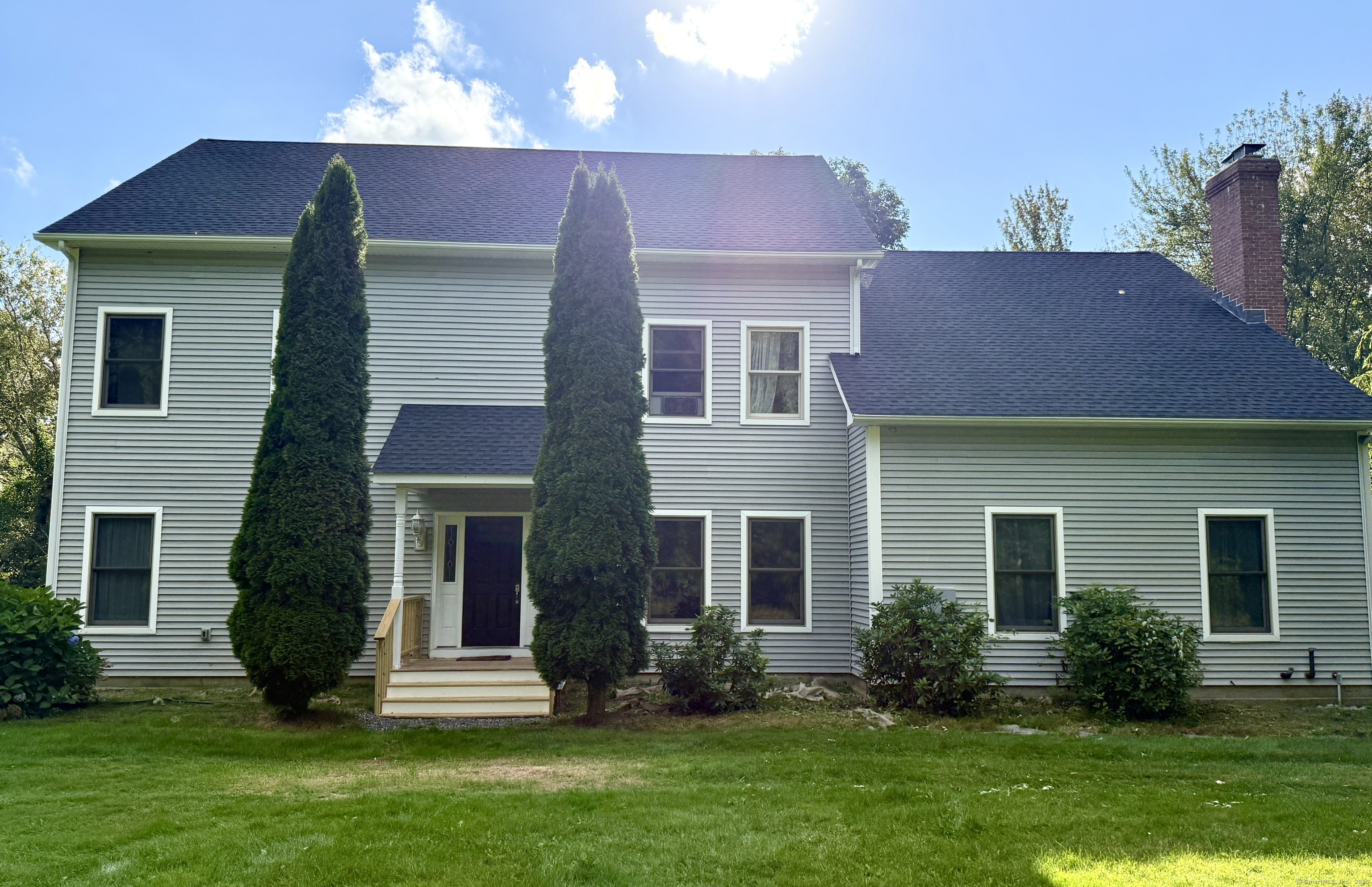 a front view of a house with a yard and a tree
