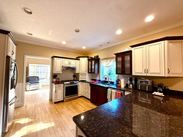 a large kitchen with stainless steel appliances granite countertop a stove top oven a sink dishwasher and cabinets with wooden floor