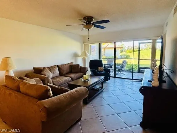a living room with furniture a flat screen tv and a floor to ceiling window