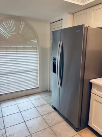 a view of a refrigerator in kitchen and an empty room
