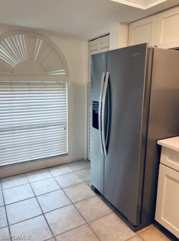 a view of a refrigerator in kitchen and an empty room