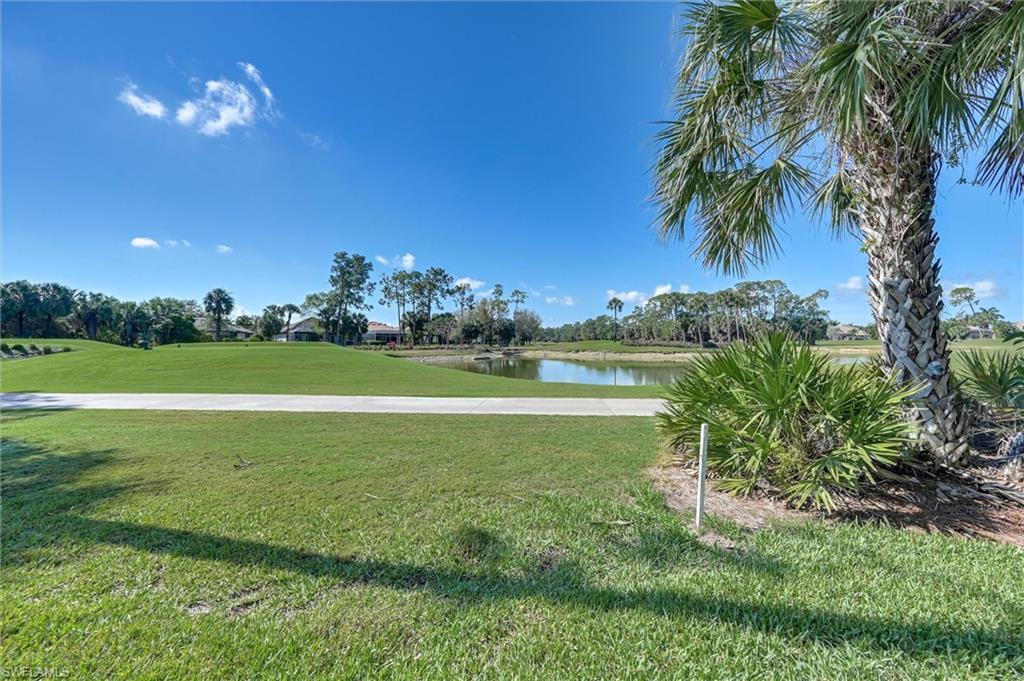 7587 Moorgate Point Way Naples, FL 34113 - Photo 9 of 50 Expansive green space with a water feature, mature palm trees, and a paved pathway