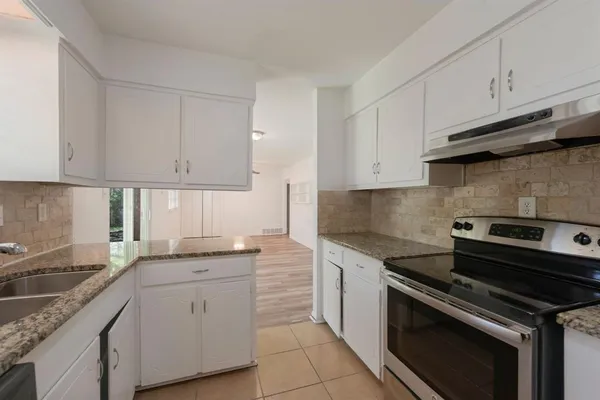 a kitchen with granite countertop white cabinets and stainless steel appliances