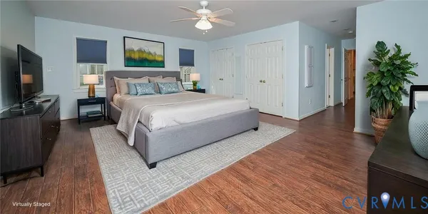 an empty room with wooden floor chandelier fan and windows