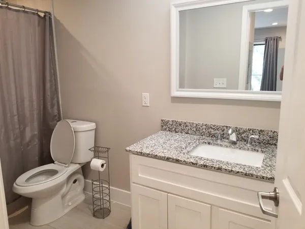 a bathroom with a granite countertop toilet sink and mirror