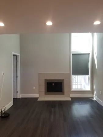 an empty room with wooden floor fireplace and windows
