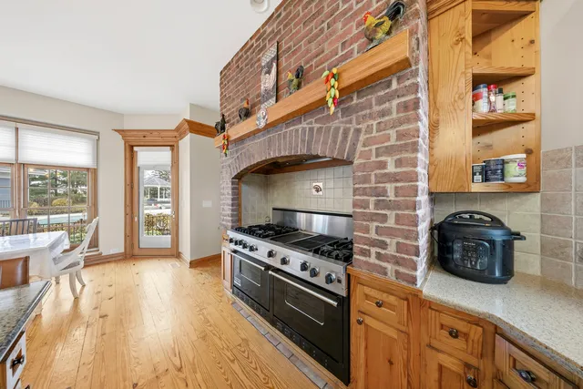 a kitchen with stainless steel appliances a stove a sink a refrigerator wooden floor and cabinets