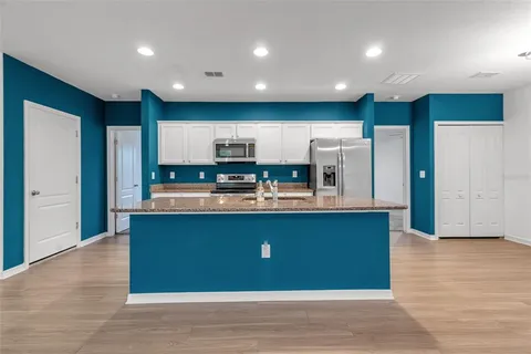 an open kitchen with kitchen island wooden floor and center island