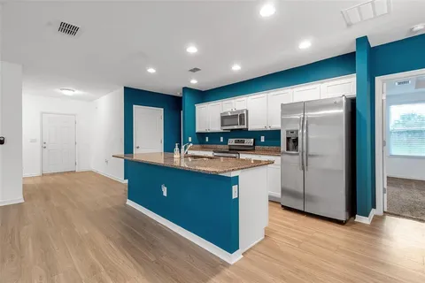 an empty room with wooden floor chandelier fan and windows