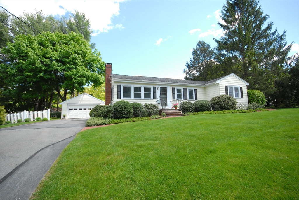 a front view of a house with a garden and trees