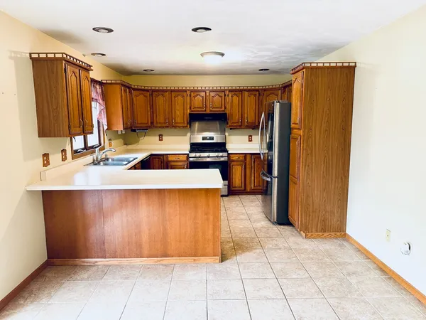 a kitchen with kitchen island granite countertop a sink cabinets and stainless steel appliances
