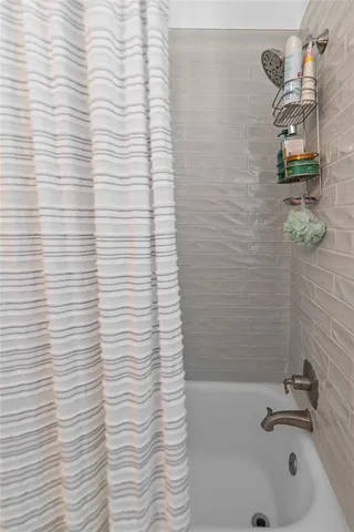 a bathroom with a white bathtub and shower