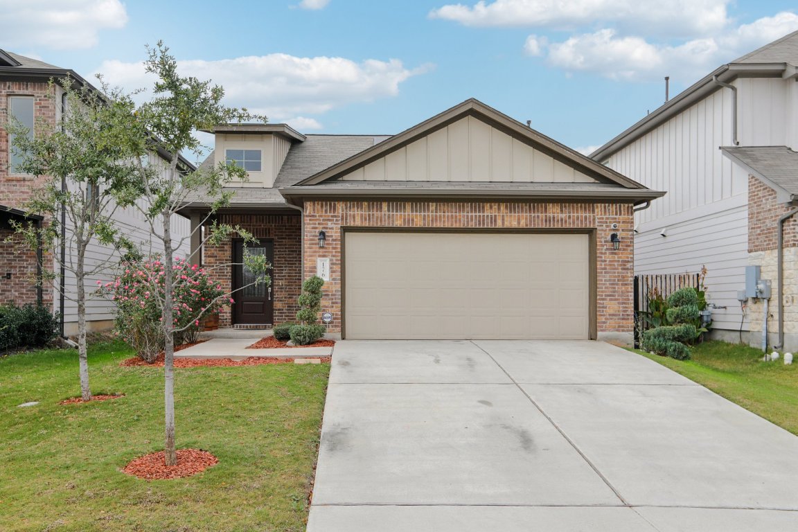 View of front of house featuring a garage, driveway, brick siding, and a front lawn
