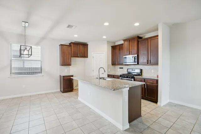 a view of kitchen with stainless steel appliances granite countertop a stove top oven a sink and a refrigerator