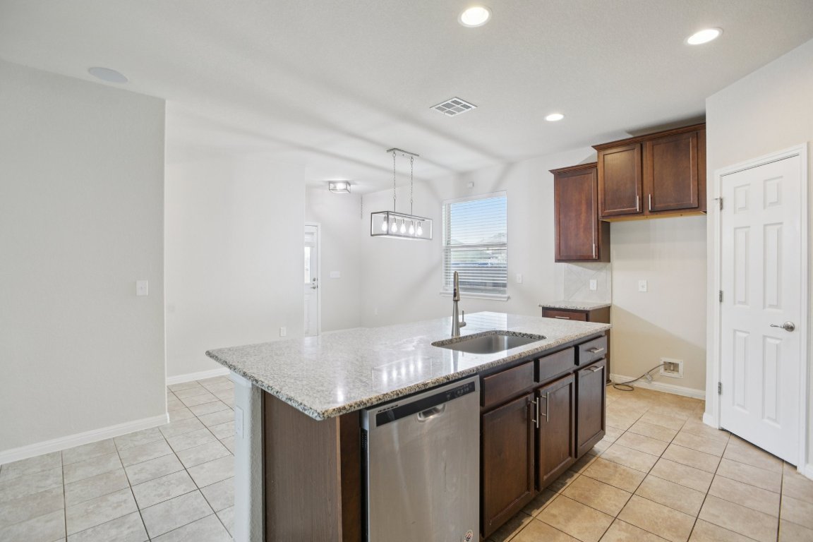 176 Mayney Ln. Leander, TX 78641 - Photo 11 of 34 Kitchen featuring light stone countertops, stainless steel dishwasher, light tile patterned flooring, pendant lighting, and recessed lighting