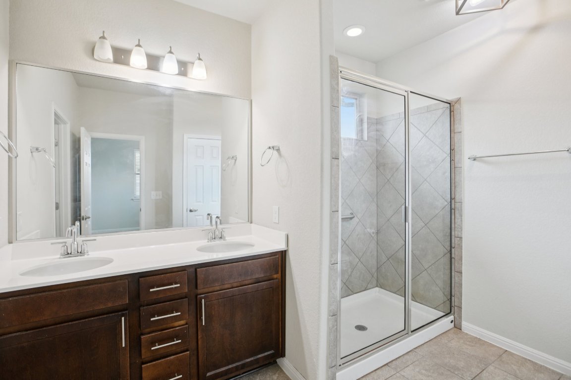 176 Mayney Ln. Leander, TX 78641 - Photo 18 of 34 Bathroom with double vanity, a stall shower, and light tile patterned floors