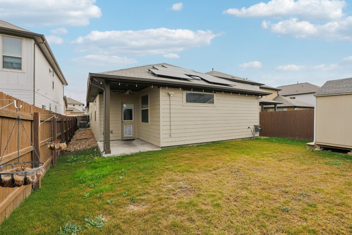 176 Mayney Ln. Leander, TX 78641 - Photo 30 of 34 Back of house featuring a patio area, roof mounted solar panels, a fenced backyard, ceiling fan, and a storage shed