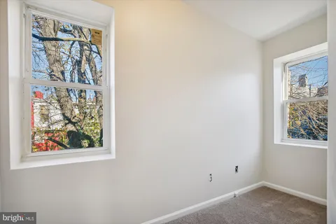 an empty room with a window and painting on the wall