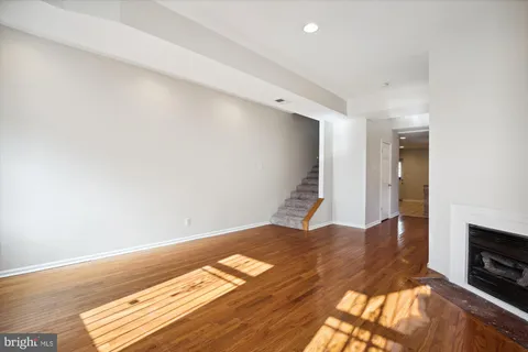 a view of an empty room with wooden floor and a fireplace