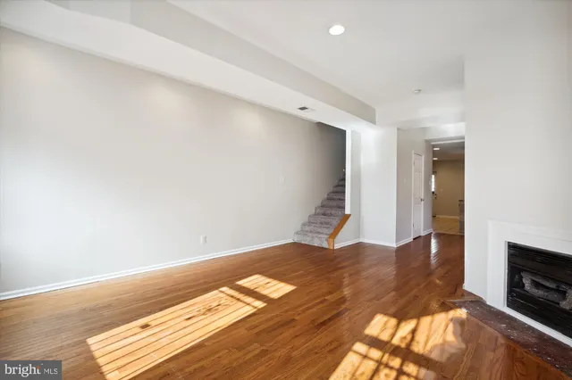 a view of an empty room with wooden floor and a fireplace