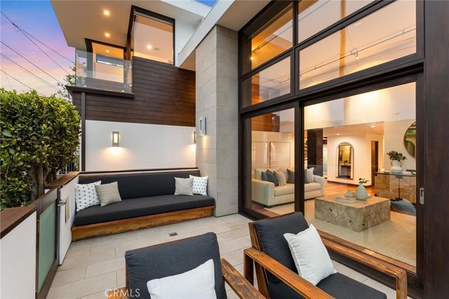 a outdoor kitchen with stainless steel appliances granite countertop a stove a sink a dining table and chairs