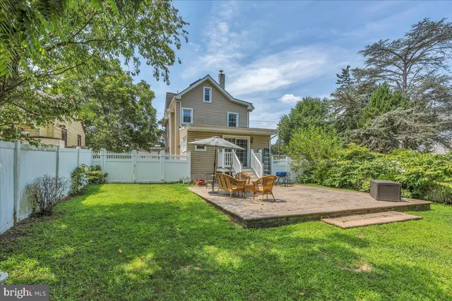 a view of a backyard with table and chairs and potted plants and large trees