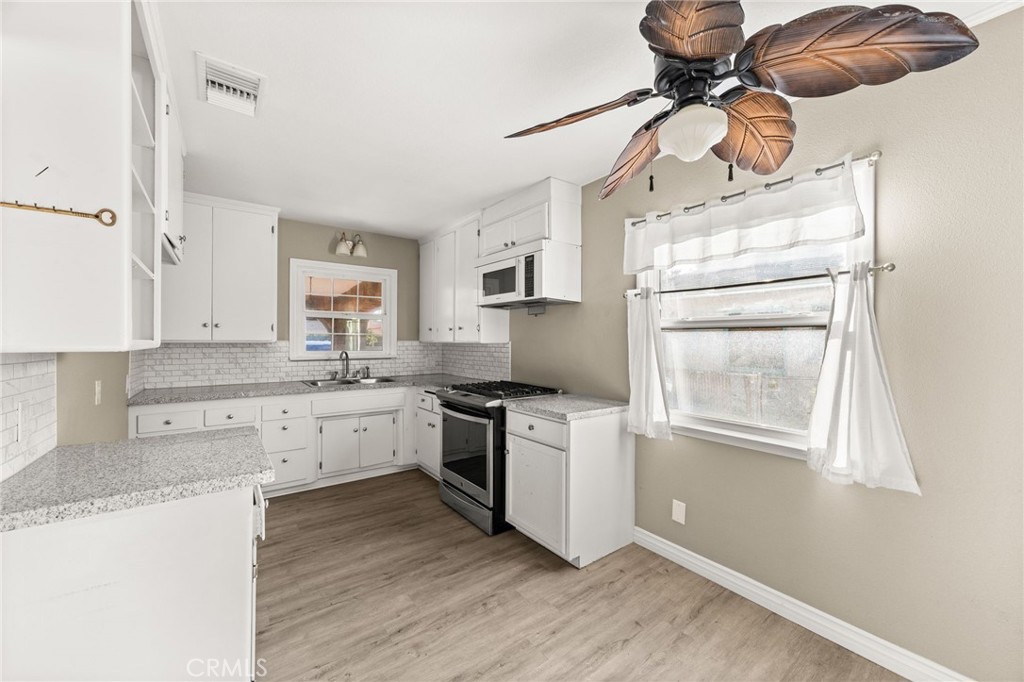 3869 Shamrock Avenue Riverside, CA 92501 - Photo 5 of 34 a kitchen with stainless steel appliances granite countertop a stove a refrigerator and white cabinets with wooden floor