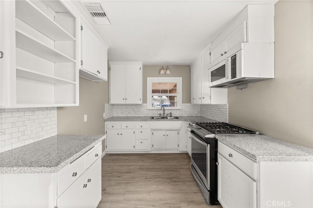 3869 Shamrock Avenue Riverside, CA 92501 - Photo 6 of 34 a kitchen with granite countertop white cabinets and white appliances