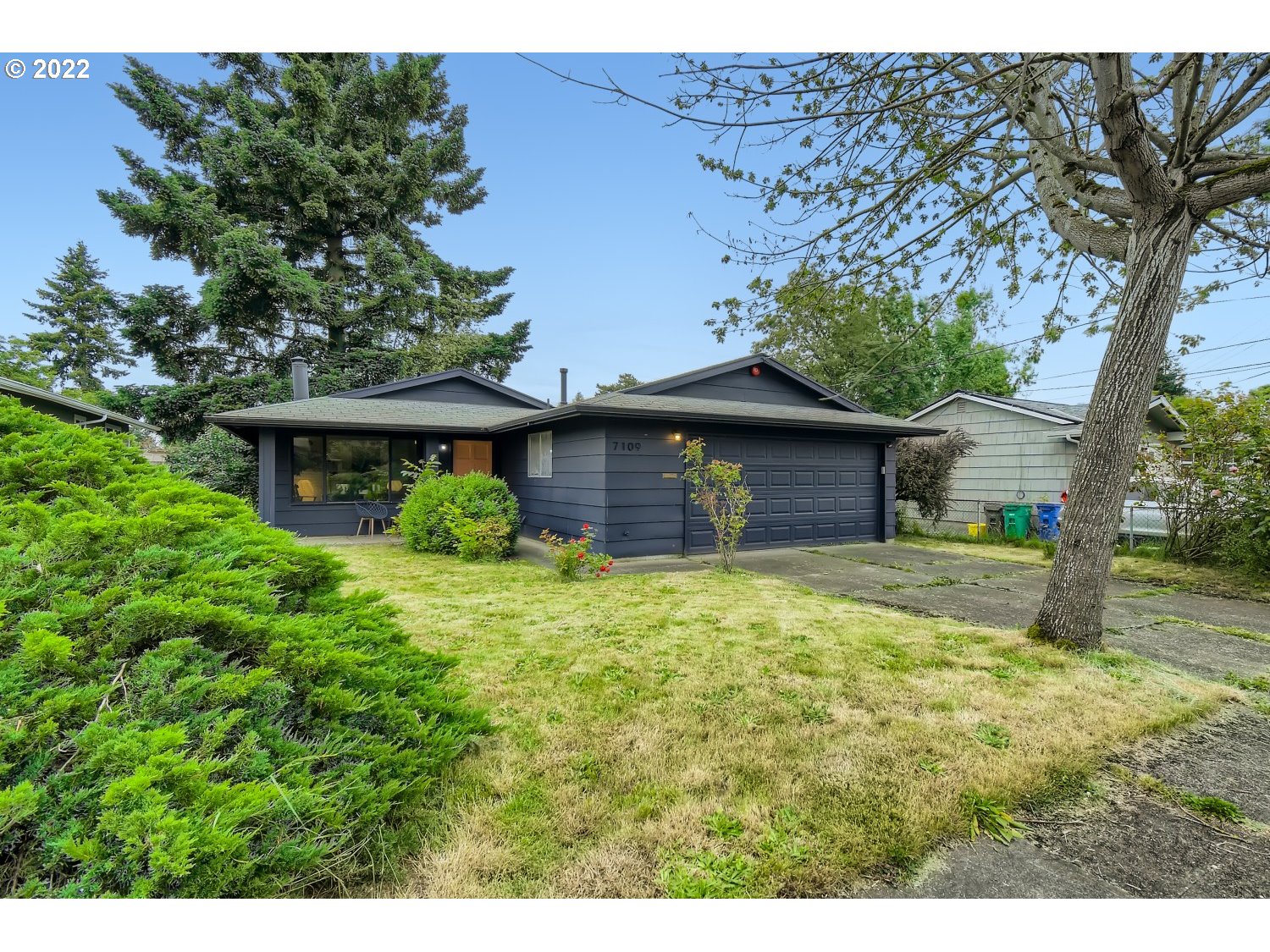 a front view of a house with a garden and tree