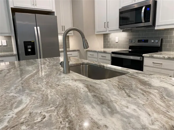 a kitchen with stainless steel appliances granite countertop a sink a stove and microwave