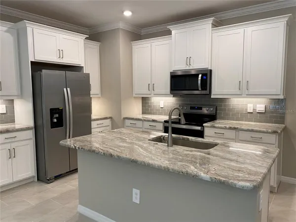 a kitchen with granite countertop a refrigerator stove and microwave