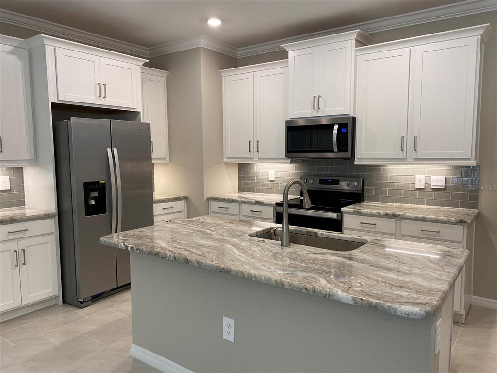 124 Soliera Street Nokomis, FL 34275 - Photo 10 of 43 a kitchen with granite countertop a refrigerator stove and microwave