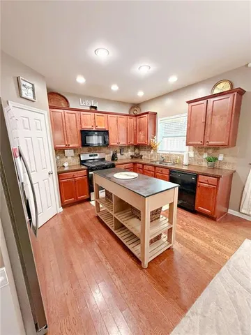 a living room with stainless steel appliances granite countertop furniture wooden floor and a window