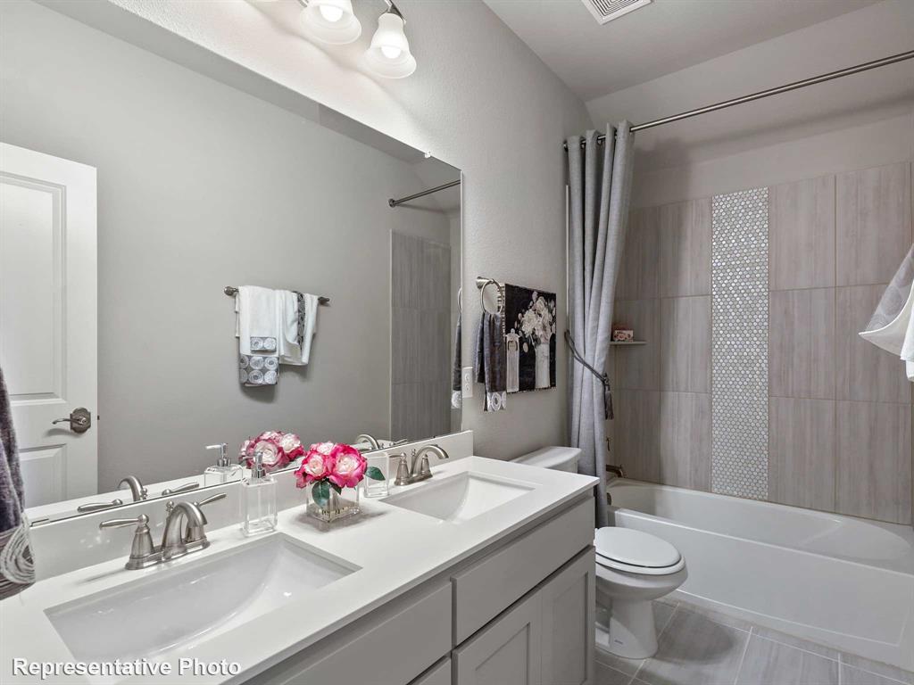 1143 Rothland Lane Red Oak, TX 75154 - Photo 13 of 18 Bathroom featuring a dual vanity with undermount sinks and brushed nickel fixtures, a tub/shower combination with subway tile surround, a decorative mosaic tile accent, and light gray tile flooring