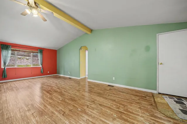 a view of an empty room with window and wooden floor