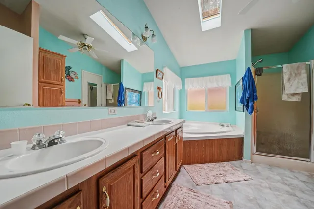 a bathroom with a sink double vanity granite tub shower and a mirror