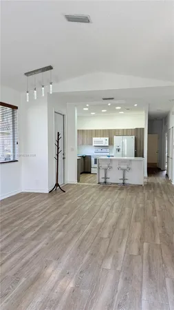 a kitchen with a sink dishwasher a stove and white cabinets with wooden floor