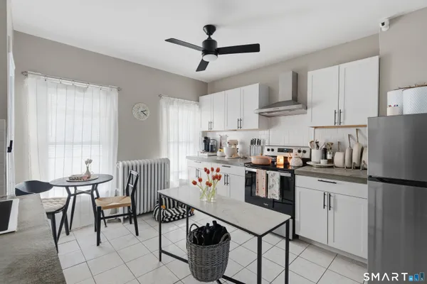 a kitchen with stainless steel appliances granite countertop a stove a sink dishwasher a dining table and chairs with white cabinets