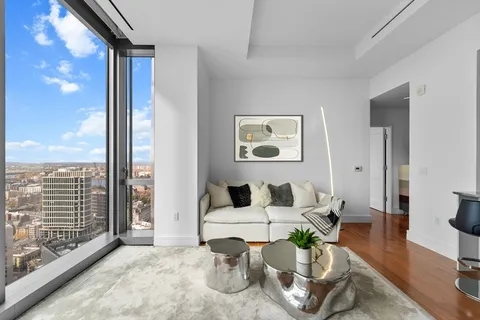 a living room with furniture large window and wooden floor