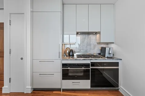 a kitchen with granite countertop a stove and white cabinets