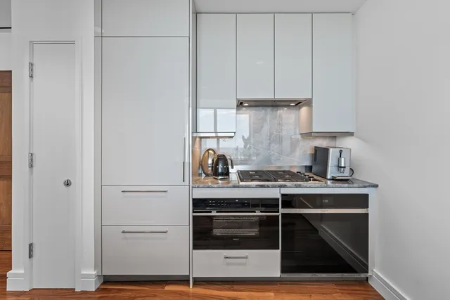 a kitchen with granite countertop a stove and white cabinets